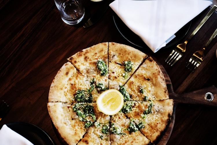 A pizza topped with arugula, cheese, and a wedge of lemon from Giulia.